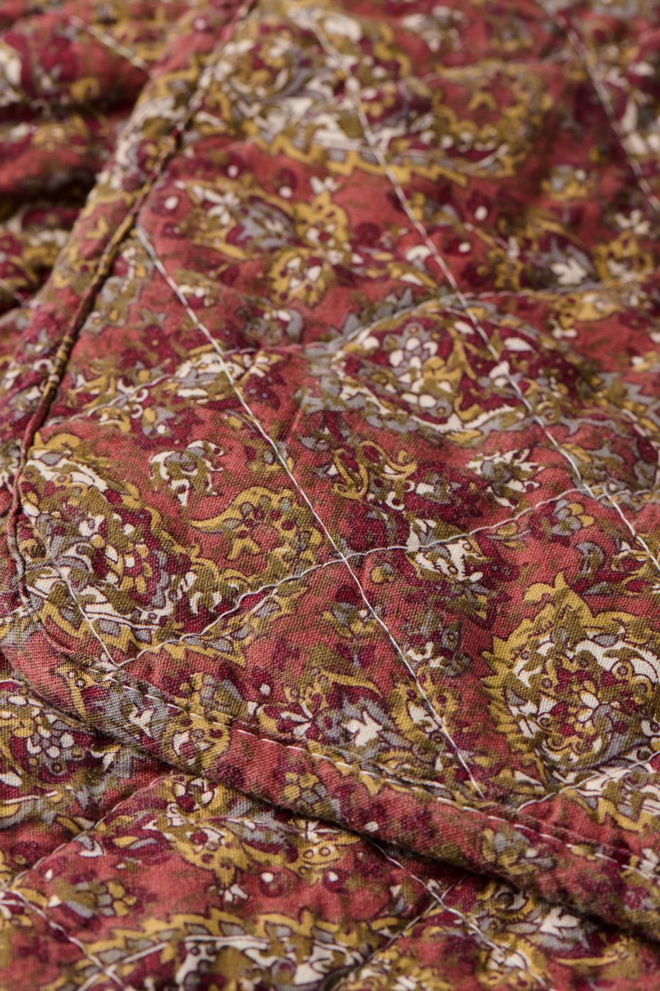 Nærbillede af quilt fra Ib Laursen med detaljeret paisleymønster i varme rosa og grønne farver