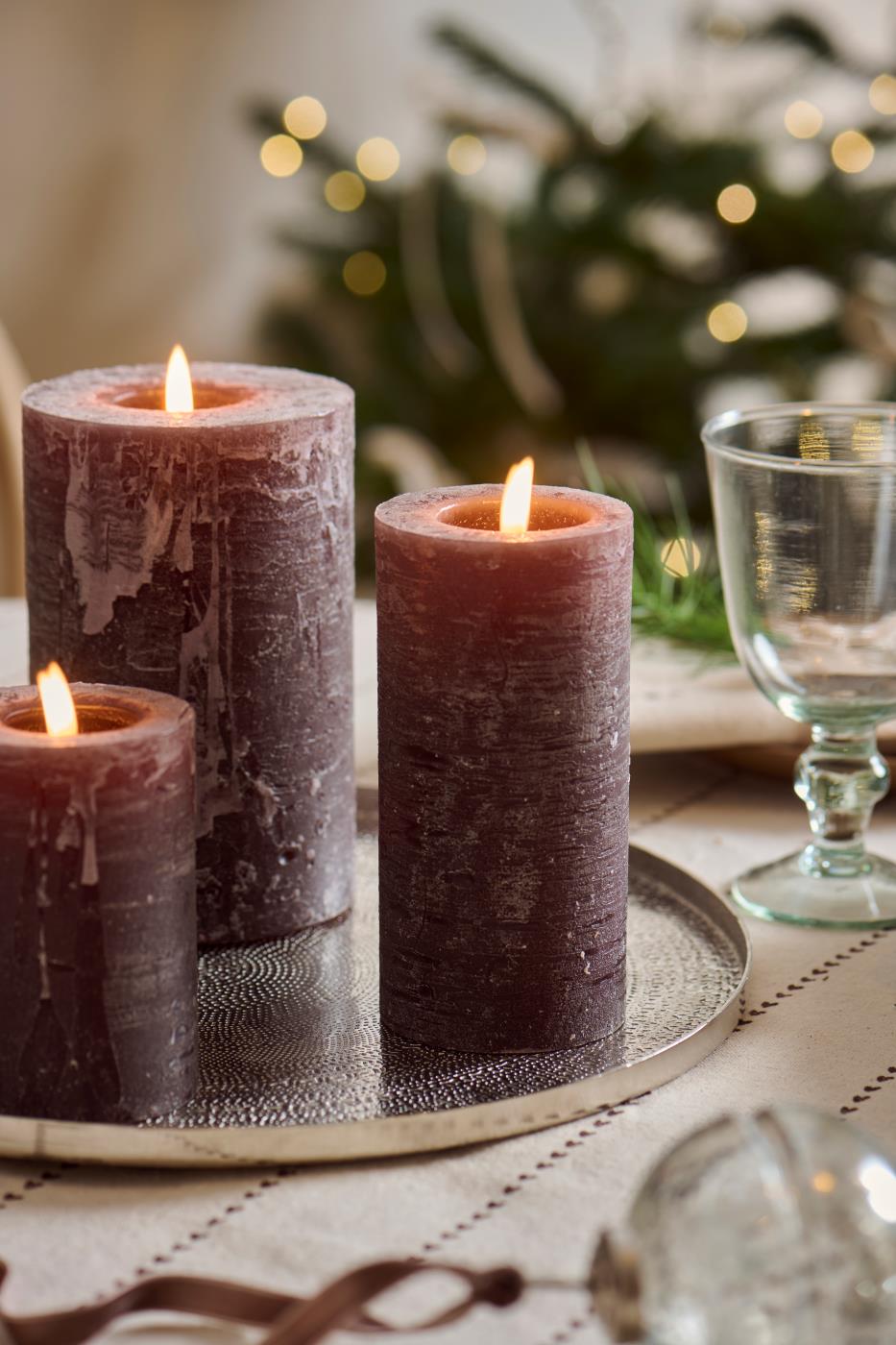 Chokoladebrune bloklys med levende flammer på dekorationsfad ved stemningsfuldt julebord
