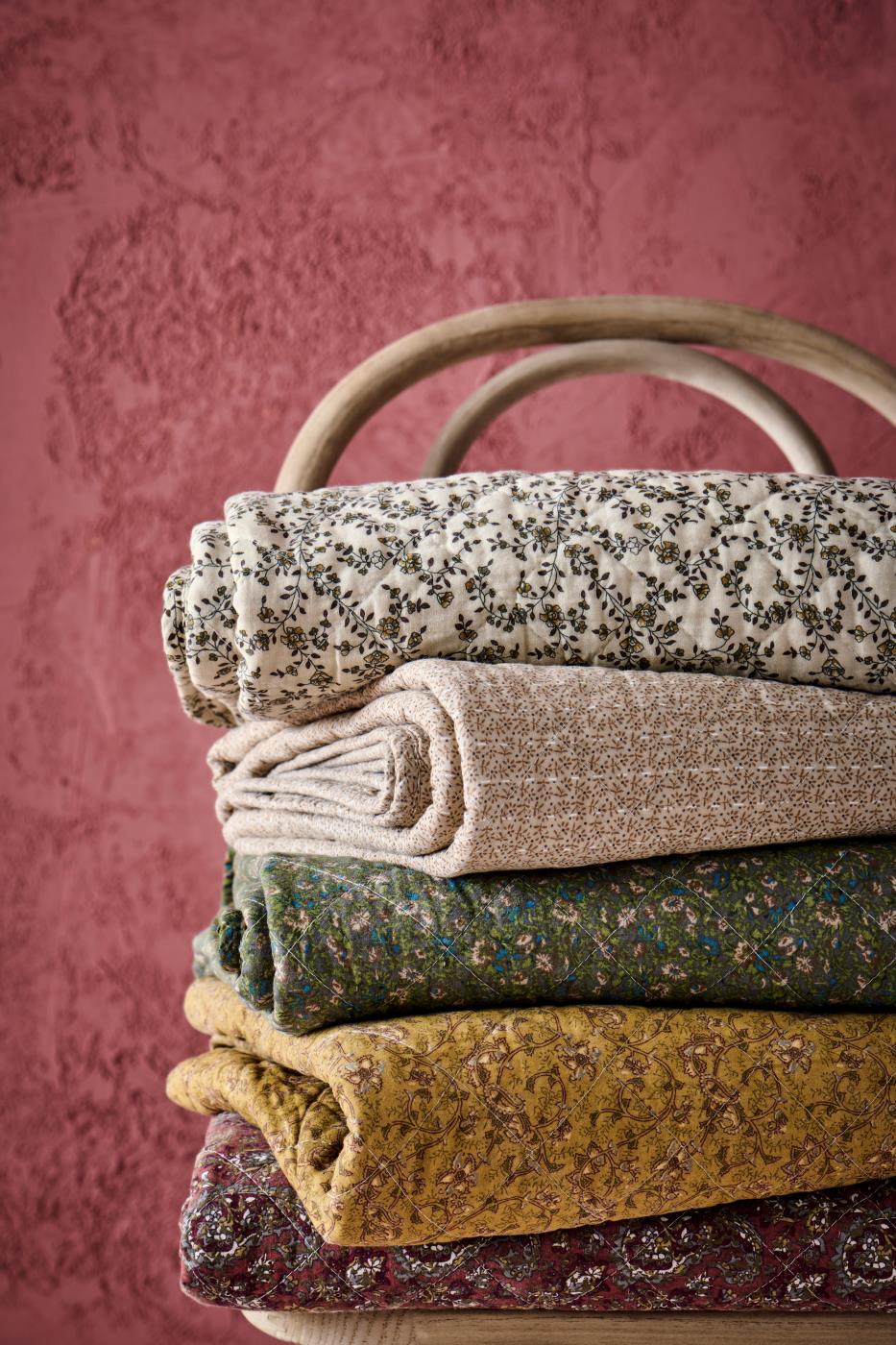 Stak af blomstrede og mønstrede quilts fra Ib Laursen i varme og afdæmpede farver