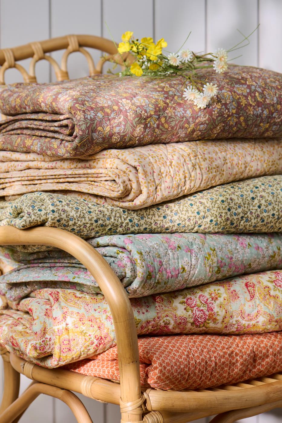 Foldede quilts fra Ib Laursen med forskellige blomstrede og mønstrede tekstiler i varme farver