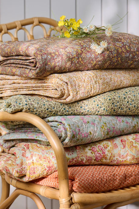 Foldede quilts fra Ib Laursen med forskellige blomstrede og mønstrede tekstiler i varme farver