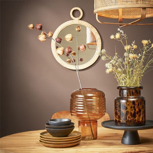 Rundt Kaj spejl med ratan ramme på grå væg med tørrede blomster i vaser i forgrunden