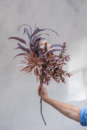 Kunstige efterårsblomster og eukalyptus samlet i en luftig buket med rosa, lilla og brunlige nuancer.