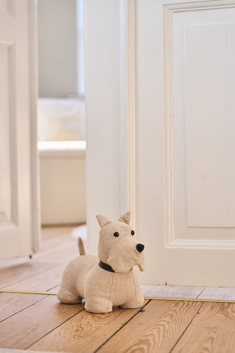 Dørstopper hvid og beige skottehund fra Speedtsberg holder en hvid dør