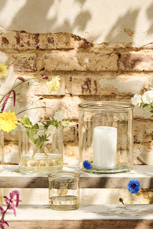 Klart Hannah cylinderglas fra Ib Laursen med hvidt bloklys blandt små glasvaser og blomster