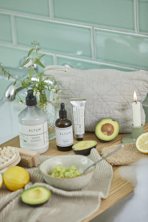 Badeværelsesmiljø med naturlige plejeprodukter, avocado og ALTUM badehandske i jute til kropspleje.