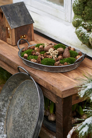 Oval Urban Garden bakke med mos, kogler og naturmaterialer som vinterdekoration på et træbord