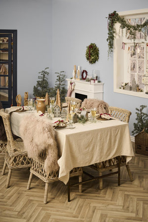 Naturfarvet dug fra Ib Laursen på et hyggeligt julebord med grønne grene, lysestager og klassisk julepynt