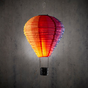 Stor hængende solcelle luftballon i orange, rød, lilla og blå med LED flammeeffekt og sort kurv til haven