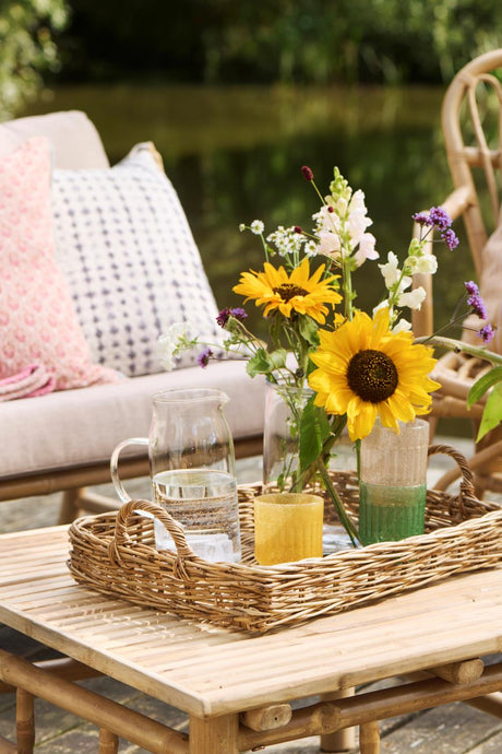 Bakke på havebord med blomster i cylinderglasvase