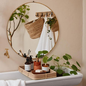 Ib Laursen ALTUM Golden Grass duftlys på bakke over badekar med sæber og pensler med rundt spejl på væg