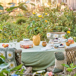 Ib Laursen grøn Emil dug 150x250 cm pryder et dækket havebord med forårsblomster