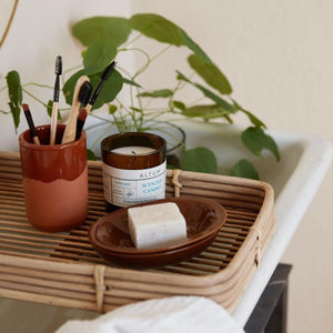 Nærbillede af Ib Laursen ALTUM Golden Grass duftlys på bakke over badekar med sæbe og pensler